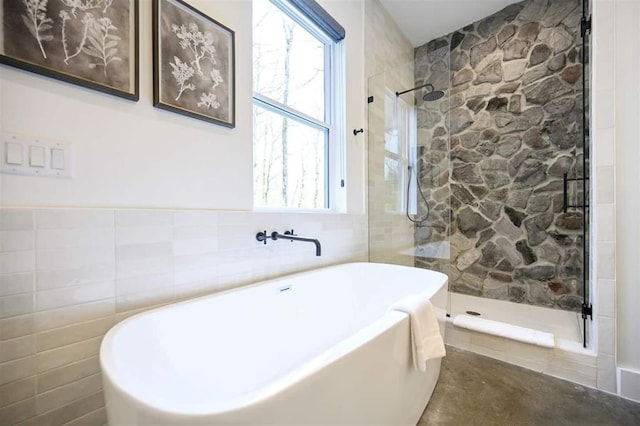 bathroom with tile walls and independent shower and bath