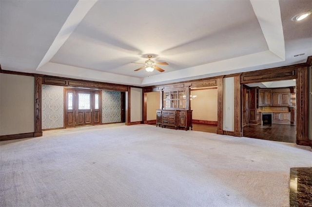 interior space featuring a raised ceiling, ceiling fan, and carpet flooring