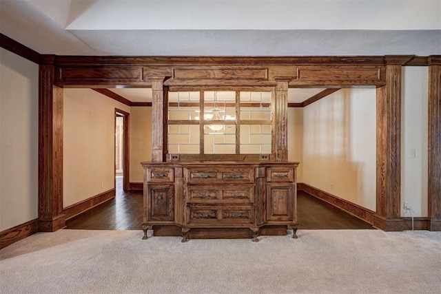 interior space with ornate columns, dark colored carpet, and crown molding