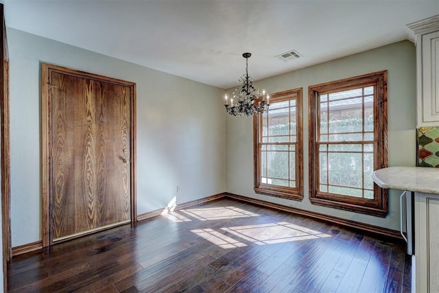 unfurnished dining area featuring dark hardwood / wood-style floors and a chandelier