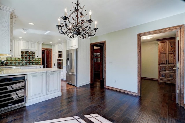 kitchen with decorative backsplash, high end refrigerator, beverage cooler, hanging light fixtures, and white cabinets