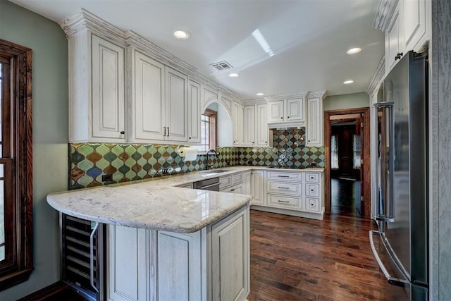 kitchen with appliances with stainless steel finishes, white cabinetry, sink, kitchen peninsula, and light stone counters