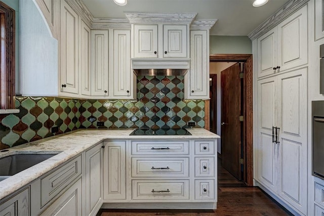 kitchen with light stone counters, white cabinetry, black electric stovetop, and extractor fan