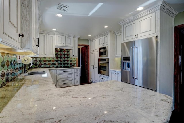 kitchen featuring decorative backsplash, sink, white cabinetry, light stone countertops, and appliances with stainless steel finishes