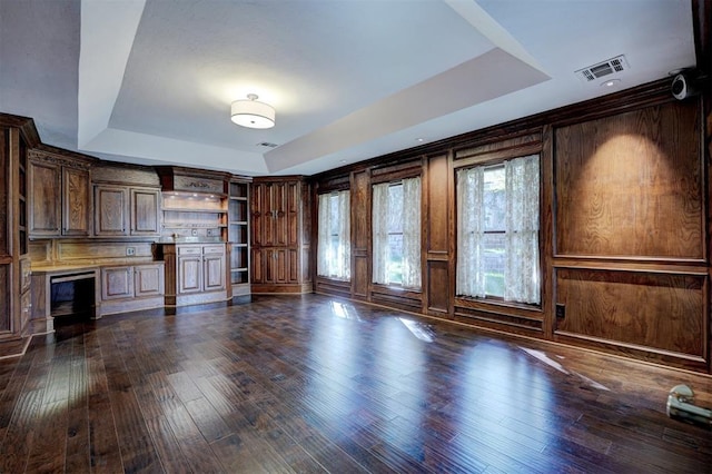 unfurnished living room with a tray ceiling and dark hardwood / wood-style flooring