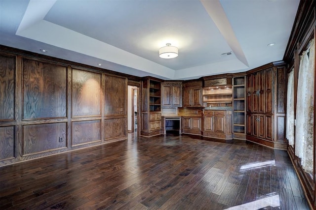 kitchen with dark wood-type flooring, dark brown cabinets, and a raised ceiling