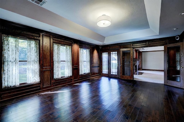 unfurnished room featuring french doors, a wealth of natural light, hardwood / wood-style floors, and a tray ceiling