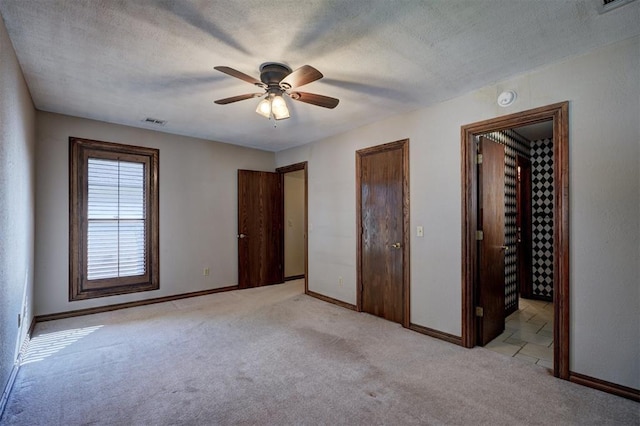 unfurnished bedroom with ceiling fan, light colored carpet, and a textured ceiling