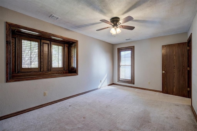 carpeted spare room featuring ceiling fan and a textured ceiling