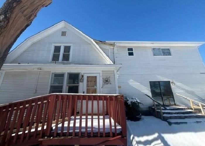 snow covered back of property featuring a wooden deck