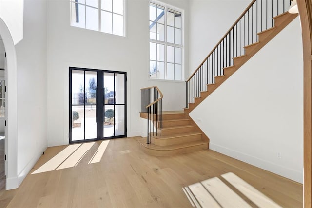 foyer featuring a towering ceiling, light hardwood / wood-style flooring, and french doors