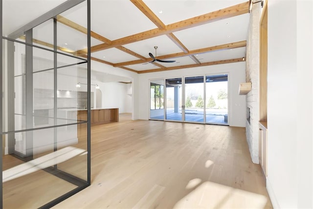 empty room with coffered ceiling, light hardwood / wood-style flooring, beam ceiling, and ceiling fan