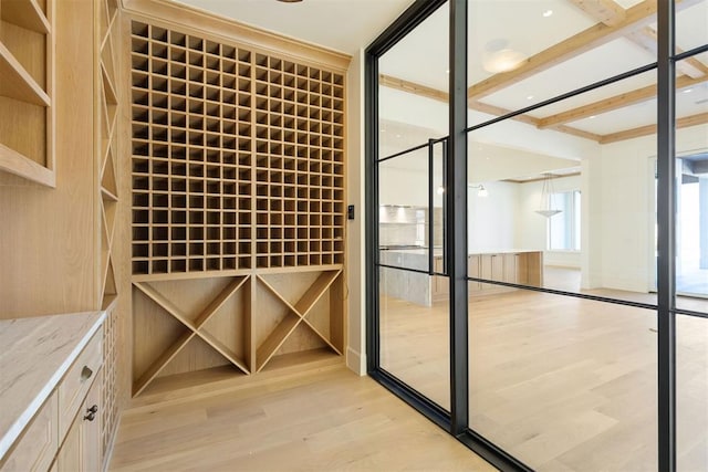 wine room featuring light hardwood / wood-style flooring and beamed ceiling