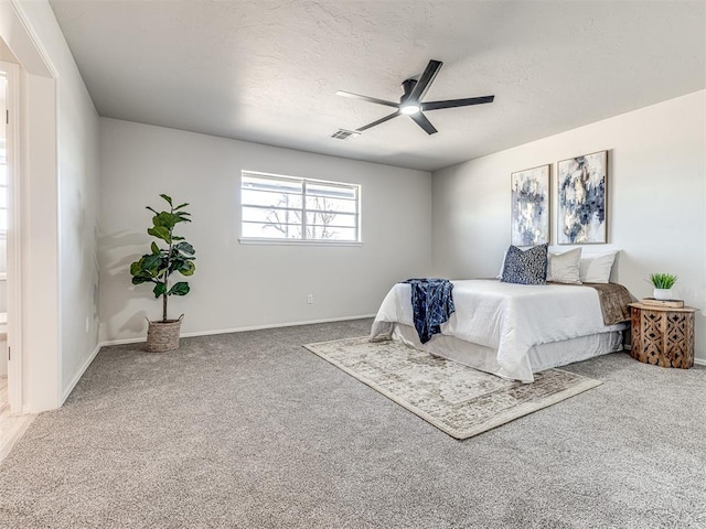 carpeted bedroom with ceiling fan and a textured ceiling