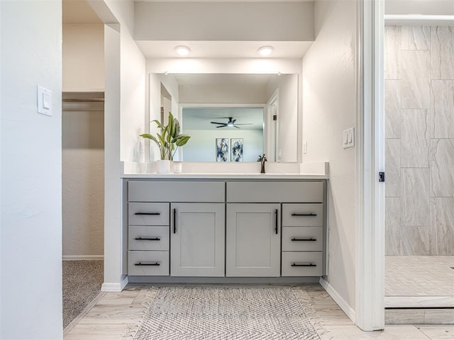 bathroom featuring ceiling fan, a tile shower, and vanity