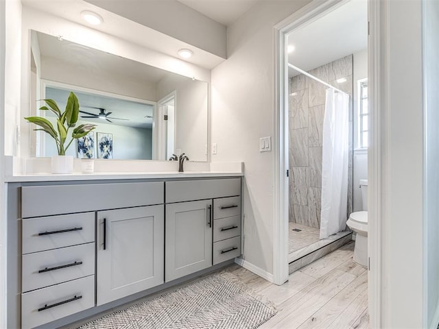 bathroom featuring toilet, hardwood / wood-style floors, a shower with curtain, ceiling fan, and vanity