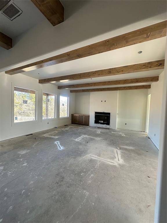 unfurnished living room with visible vents and beam ceiling