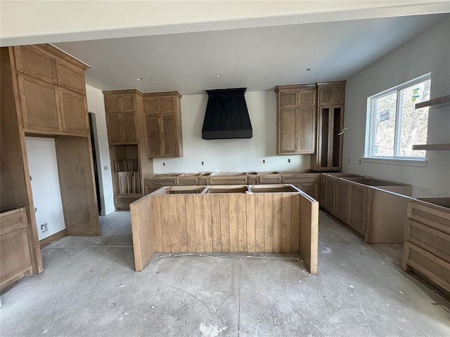 kitchen with brown cabinetry, unfinished concrete floors, a kitchen island, and open shelves