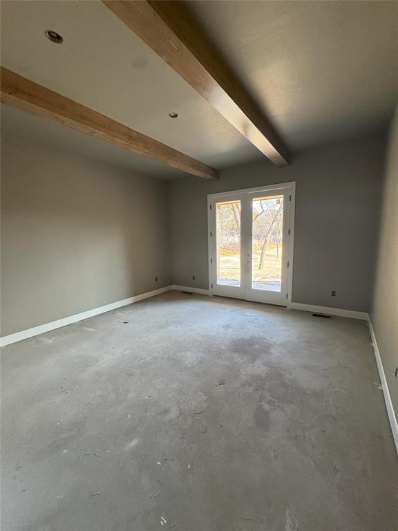 empty room featuring beamed ceiling, unfinished concrete flooring, visible vents, and baseboards