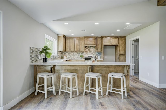 kitchen featuring electric range, light hardwood / wood-style flooring, backsplash, kitchen peninsula, and lofted ceiling