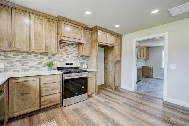 kitchen with light brown cabinets, tasteful backsplash, light hardwood / wood-style flooring, and stainless steel gas range oven