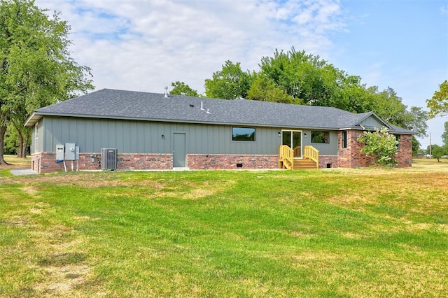 rear view of property with central AC unit and a yard