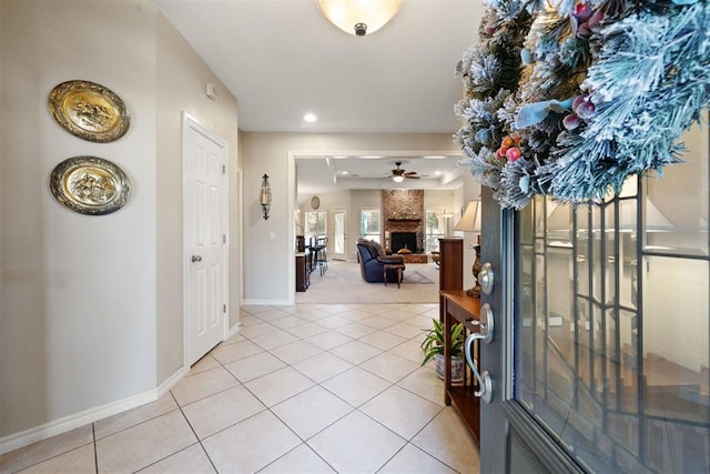 entrance foyer with ceiling fan, a fireplace, and light tile patterned floors