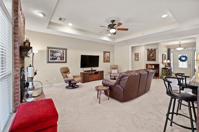 living room with ceiling fan, a raised ceiling, and light carpet