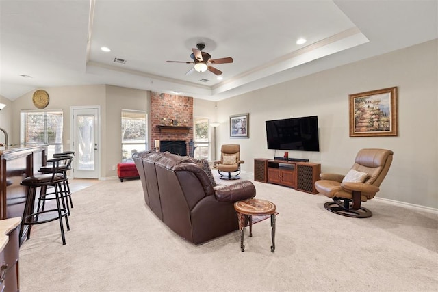 living room with light carpet, a raised ceiling, ceiling fan, and a fireplace