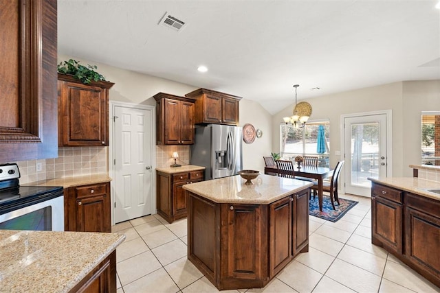 kitchen with a center island, an inviting chandelier, hanging light fixtures, appliances with stainless steel finishes, and tasteful backsplash