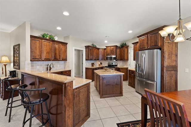 kitchen featuring kitchen peninsula, appliances with stainless steel finishes, a chandelier, and decorative backsplash