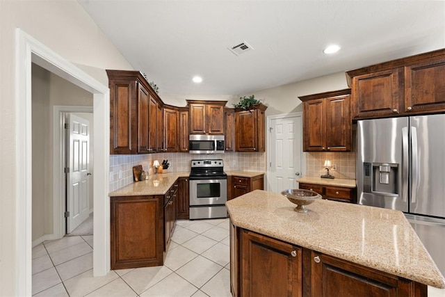 kitchen with tasteful backsplash, a center island, light tile patterned flooring, and appliances with stainless steel finishes