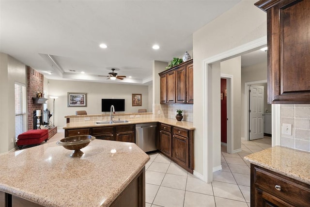 kitchen featuring dark brown cabinetry, sink, a raised ceiling, stainless steel dishwasher, and decorative backsplash