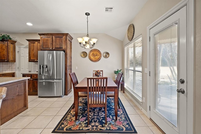 dining room featuring light tile patterned floors, vaulted ceiling, and a notable chandelier