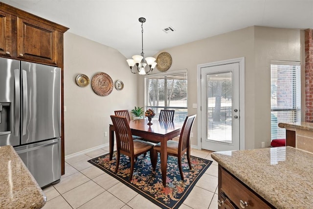 tiled dining room featuring a notable chandelier, a healthy amount of sunlight, and lofted ceiling