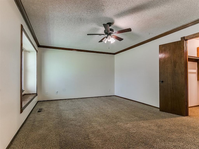 carpeted empty room featuring ceiling fan, ornamental molding, and a textured ceiling