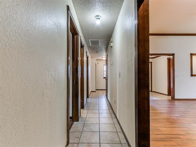 hall with light tile patterned floors and a textured ceiling