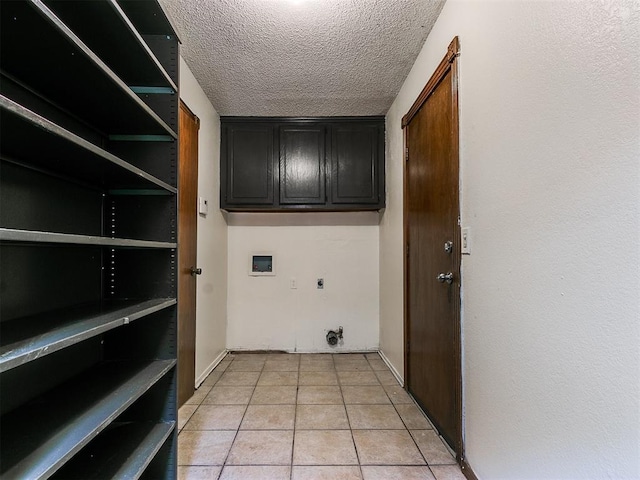 laundry area featuring electric dryer hookup, cabinets, washer hookup, light tile patterned floors, and a textured ceiling