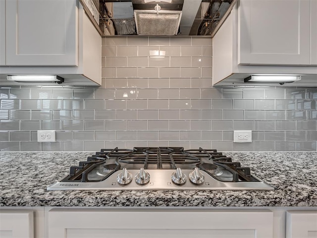 kitchen featuring white cabinets, light stone countertops, tasteful backsplash, and stainless steel gas cooktop