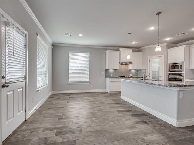 kitchen with light stone countertops, appliances with stainless steel finishes, backsplash, pendant lighting, and white cabinetry