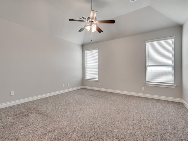 carpeted spare room with a wealth of natural light, ceiling fan, and vaulted ceiling