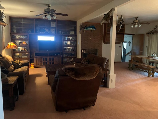 living room featuring carpet floors, built in shelves, ceiling fan, and a fireplace