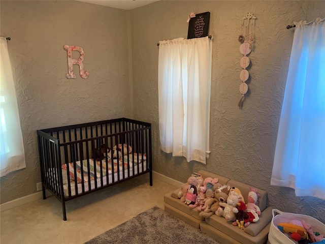 bedroom with light colored carpet and a nursery area