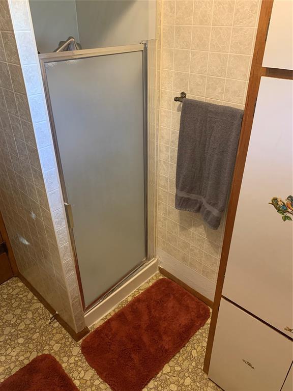 bathroom with an enclosed shower and tile walls