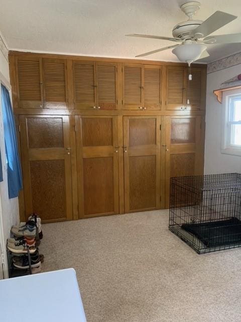 interior space featuring light carpet and ceiling fan