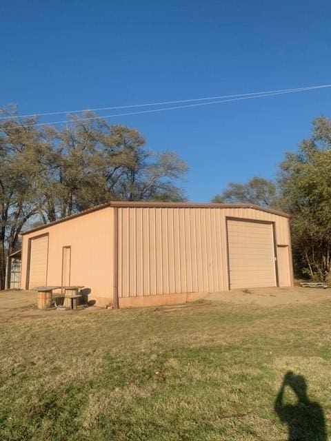 view of outdoor structure featuring a garage and a lawn