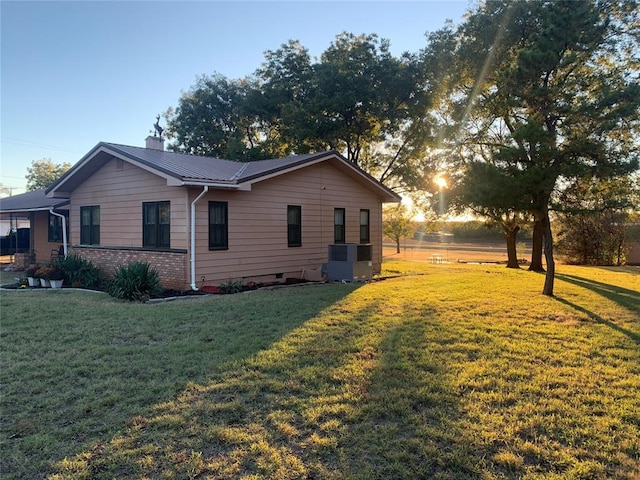 property exterior at dusk with a lawn and central AC