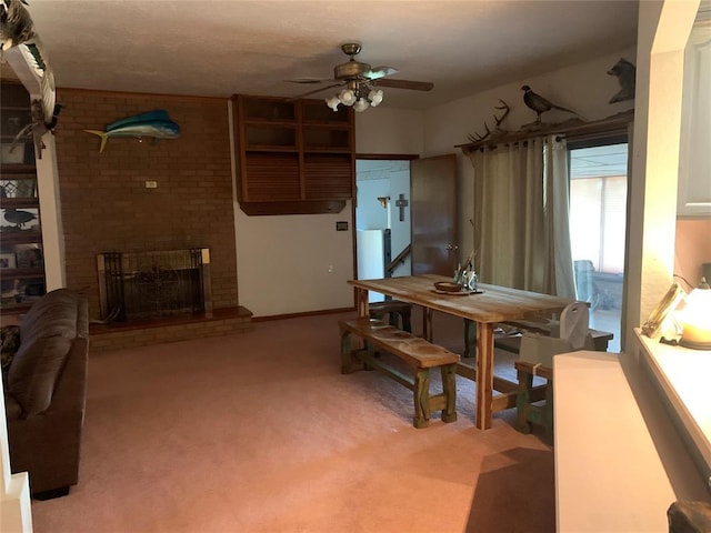 carpeted dining space featuring ceiling fan and a fireplace