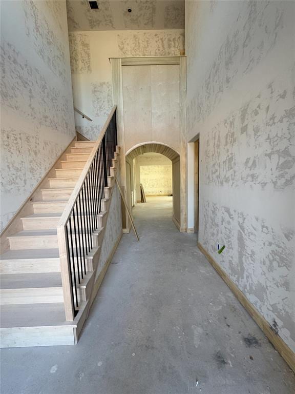 corridor featuring a high ceiling and concrete floors