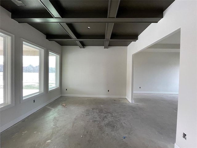 empty room featuring beam ceiling, coffered ceiling, baseboards, and concrete floors